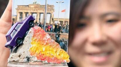 Una turista muestra un fragmento del muro de Berlín