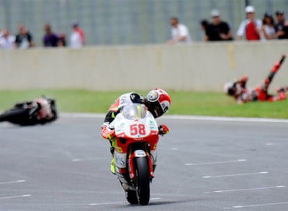 Marco Simoncelli mira a Héctor Barberá, caído en el suelo tras su choque con el piloto italiano.