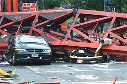 Un operario analiza los coches aplastados por un andamio tras el terremoto.