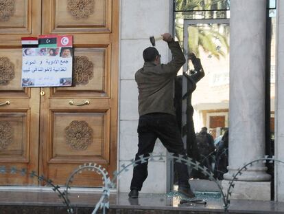 Un manifestante golpea con un martillo una ventana de la Embajada de Libia en la capital de Túnez.