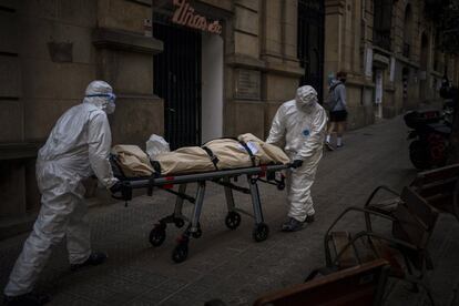 Empleados de una funeraria trasladan el cuerpo de un anciano fallecido por coronavirus en una camilla, tras retirarlo de una residencia de mayores, en Barcelona.