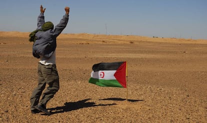 Un miembro del Frente Polisario se manifiesta ante los soldados marroqu&iacute;es, al fondo de la imagen,  apostados en el muro constru&iacute;do por Marruecos.