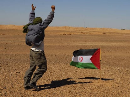 Un miembro del Frente Polisario se manifiesta ante los soldados marroqu&iacute;es, al fondo de la imagen,  apostados en el muro constru&iacute;do por Marruecos.
