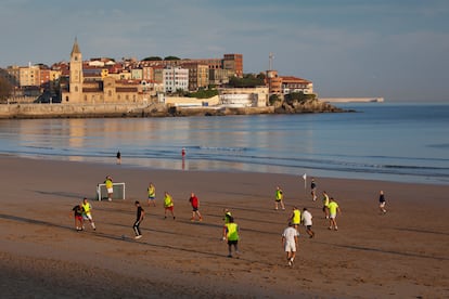 Aficionados jugando a fútbol en la playa de Gijón.