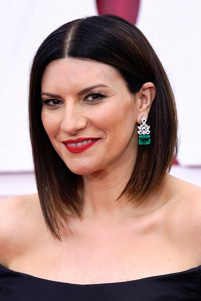 El corte bob con raya al medio de Laura Pausini dejaba ver sus espectaculares pendientes de esmeraldas de Bulgari. Completó su maquillaje con un llamativo rojo de labios.