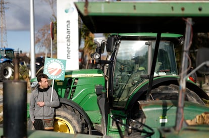 Un agricultor protesta junta a un tractor en la entrada de Mercabarna en Barcelona.