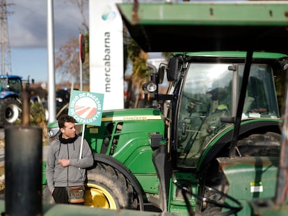 Un agricultor protesta junta a un tractor en la entrada de Mercabarna en Barcelona.