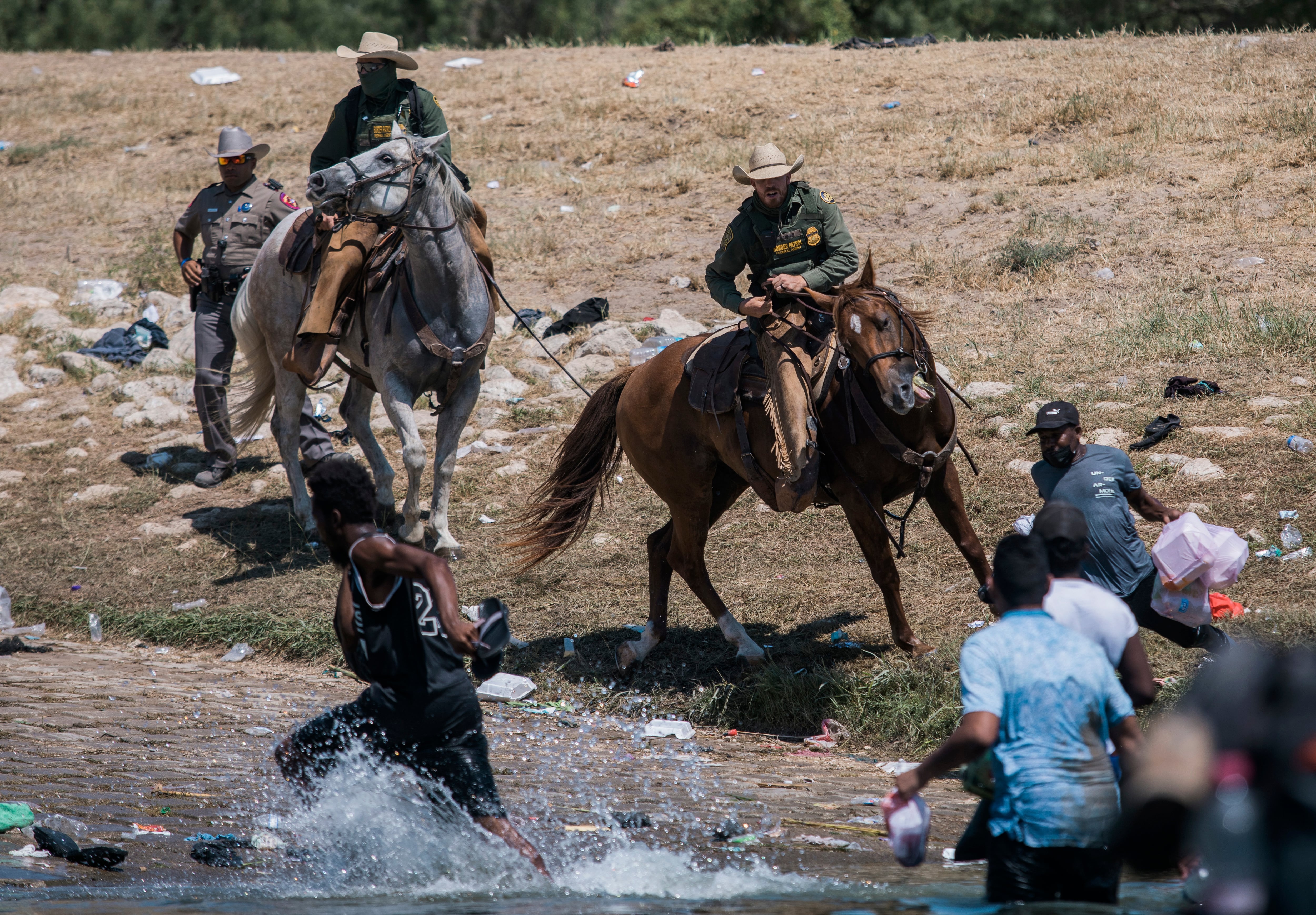 Agentes de la Oficina de Aduanas y Protección Fronteriza de EE. UU. intentan contener a los migrantes mientras cruzan el Río Grande desde Ciudad Acuña (México) hacia Del Río (Texas), el 19 de septiembre de 2021.