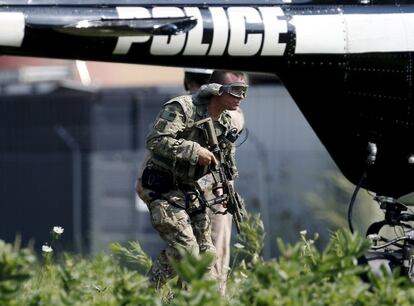 An armed police officer walks throughs a field as authorities take part in a manhunt in Fox Lake, Illinois, United States, September 1, 2015.  Police with dogs and helicopters are searching woods and swampy areas north of Chicago for three armed suspects after a police officer was shot dead on Tuesday in the suburb of Fox Lake, a local law enforcement official said.   REUTERS/Jim Young        TPX IMAGES OF THE DAY     