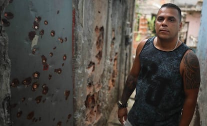 Julio César posando em um beco repleto de balazos.