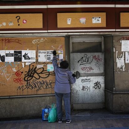 Una mujer coloca carteles en el antiguo escaparate de un local de la calle Mesones, una de las históricas del comercio en Talavera. Los negocios cerrados aparecen por doquier, junto a viejos carteles de "se alquila" o "se vende".