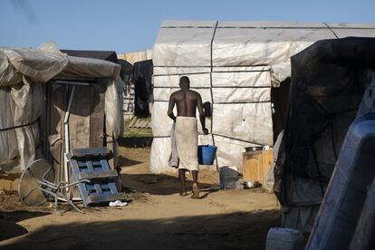 Un chico transporta agua en un cubo para bañarse en uno de los campamentos de chabolas construidos por migrantes subsaharianos en la localidad onubense de Lepe. La mayoría de las personas que viven ahí trabajan como temporeros. Un relator de la ONU publicó un informe en febrero en el que criticaba las duras condiciones de estos asentamientos. Tras visitar estas chabolas, Philip Alston sentenció: "viven como animales".