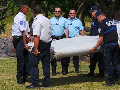 Polic&iacute;as y gendarmes transportan el aler&oacute;n hallado en Reuni&oacute;n.