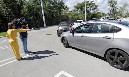 Repórter entrevista a distância um motorista na fila de um 'drive-through' de testes da Covid-19, nesta sexta-feira, no Doris Ison Health Center em Miami.