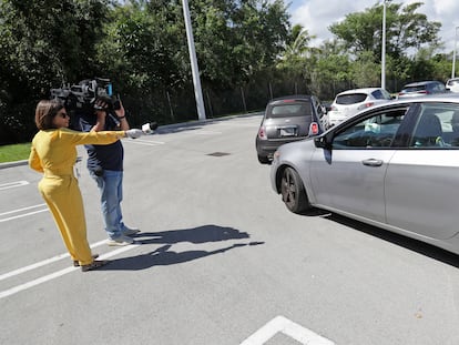 Repórter entrevista a distância um motorista na fila de um 'drive-through' de testes da Covid-19, nesta sexta-feira, no Doris Ison Health Center em Miami.