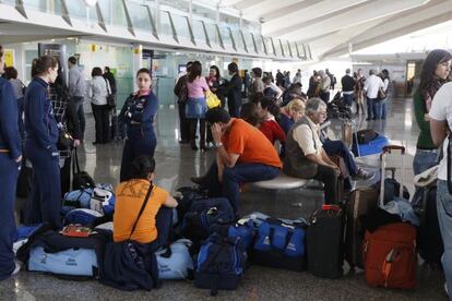 Varios viajeros esperan ante un mostrado del Aeropuerto de Loiu en una imagen de archivo.
