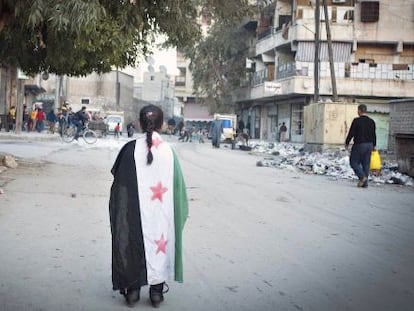 Una niña pasea envuelta en la bandera siria por Alepo, este miércoles.