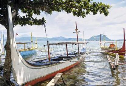 Barcos pesqueros atracados en Cor&oacute;n, una isla de playas paradisiacas y aguas turquesa. Al fondo, la isla de Basuanga.