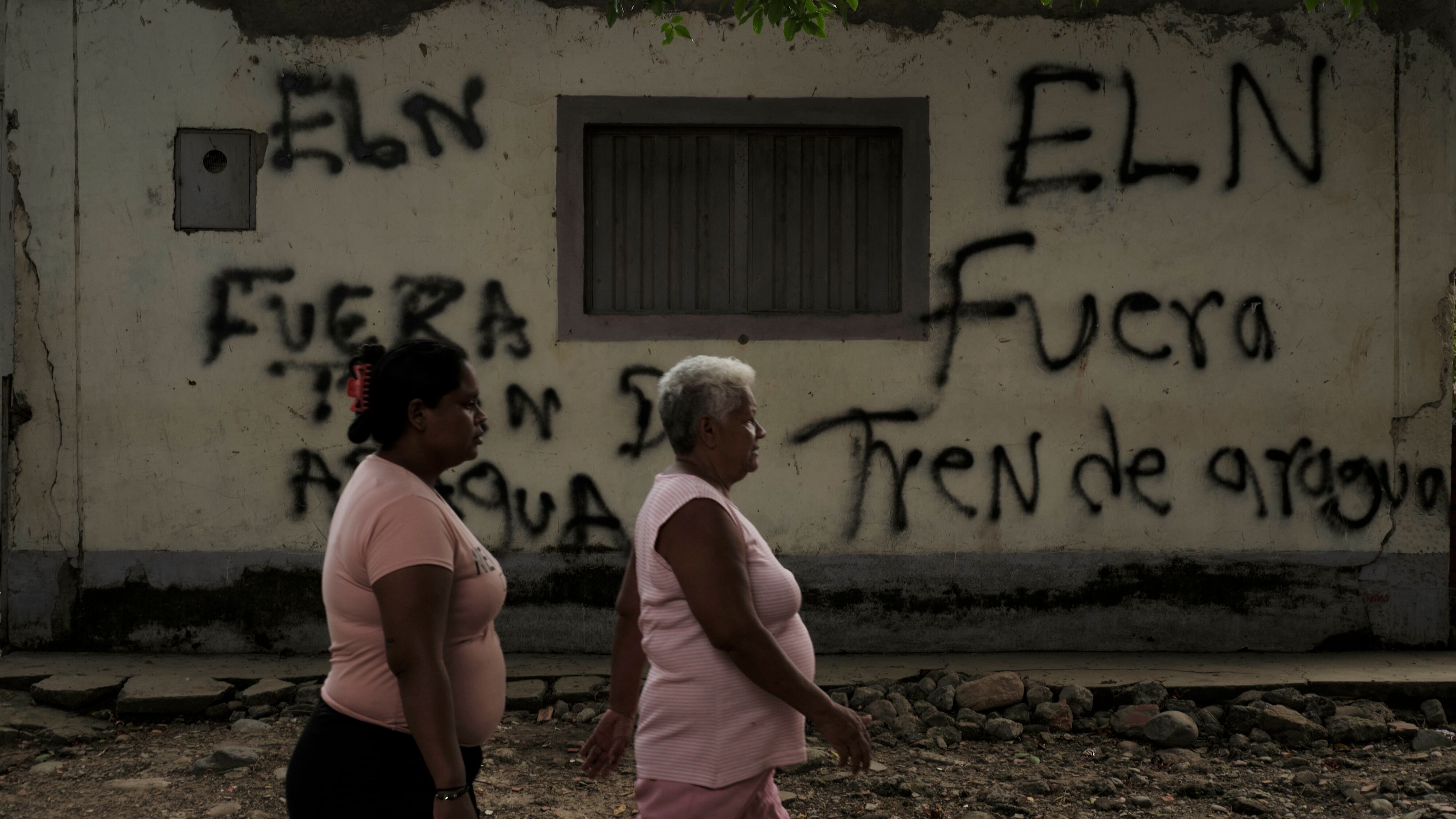 Mujeres caminan frente a un graffiti alusivo al Tren de Aragua en Cúcuta,cerca de la frontera entre Venezuela y Colombia, en marzo de 2023.
