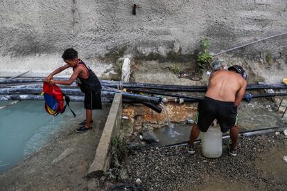 Un grupo de personas toma agua de una tubería de una construcción abandonada en la Avenida Baralt, en el centro de Caracas (Venezuela). En el anuncio hecho en cadena de radio y televisión por el líder chavista Maduro, se especificó un plan de racionamiento eléctrico "por 30 días", durante los que espera resolver los problemas del fallo que ha desatado una serie de apagones masivos desde el 7 de marzo en el país de 30 millones de habitantes.