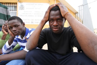 Un grupo de inmigrantes subsaharianos sentados frente a la puerta del  CETI de Melilla.