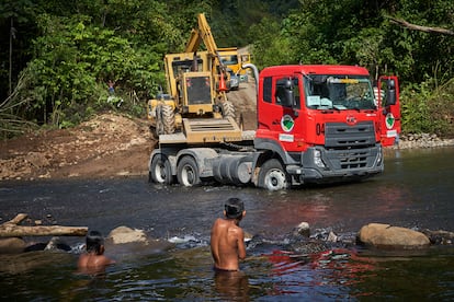 As crianças indígenas Shuar, da comunidade Kawa, observam os caminhões carregando uma escavadeira para trabalhar na nova estrada. 