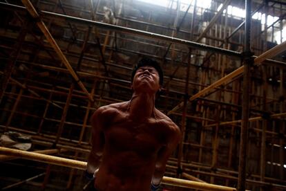 Worker Shi Shenwei performs a high bar routine on a scaffolding at the construction site of a Buddhist temple in the village of Huangshan, near Quanzhou, Fujian Province, China, September 28, 2016. REUTERS/Thomas Peter         SEARCH "BRICK CARRIER" FOR THIS STORY. SEARCH "WIDER IMAGE" FOR ALL STORIES.   TPX IMAGES OF THE DAY