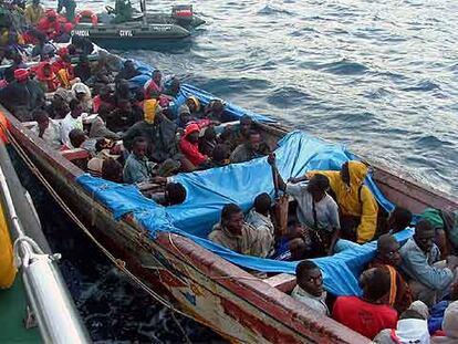 La gran piragua con 104 inmigrantes subsaharianos a bordo llega al puerto de San Sebastián de La Gomera bajo vigilancia de la Guardia Civil.