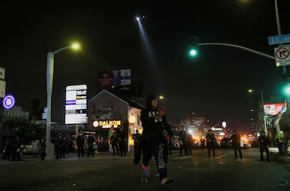 La policía, sobre el terreno y desde el aire con un helicóptero, vigilan la calle durante la noche en Los Ángeles.