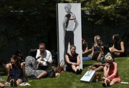 Gente en un parque londinense junto a un panel promocional de los Juegos