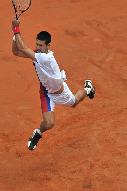 Novak Djokovic devuelve una bola mientras salta.
