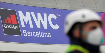 Un operario con mascarilla junto al logo del MWC de Barcelona, cancelado este año por el coronavirus.