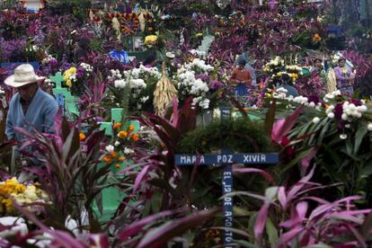 Varios personas visitan y decoran con flores y plantas las tumbas del cementerio de Zunil, Guatemala.