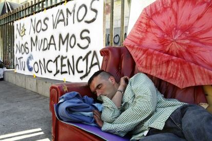 Un hombre duerme junto a uno de los carteles que permanecen hoy en la madrileña Puerta del Sol