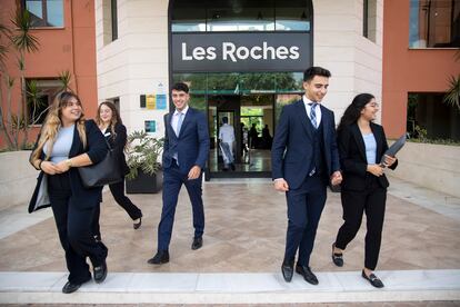 Varios estudiantes salen por la puerta principal de la escuela de negocios Les Roches. 