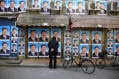 Un hombre mira un muro lleno de carteles del presidente Xi Jinping en Shangh&aacute;i
