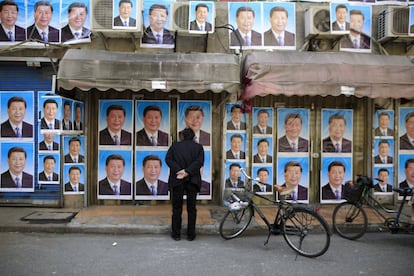 Un hombre mira un muro lleno de carteles del presidente Xi Jinping en Shangh&aacute;i