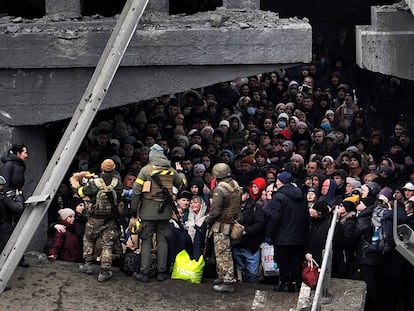 Ucranios intentan pasar por debajo de un puente destruido en Irpín, cerca de Kiev, este sábado.
