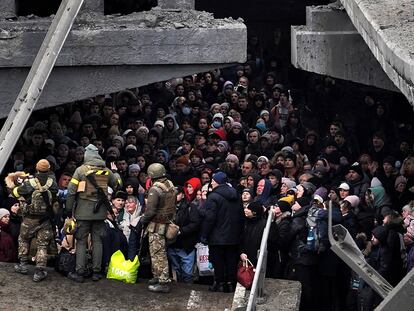 Ucranios intentan pasar por debajo de un puente destruido en Irpín, cerca de Kiev, este sábado.