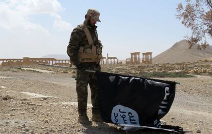 Un miembro de las fuerzas sirias retira una bandera del Estado Islámico (ISIS), el 27 de marzo de 2016.