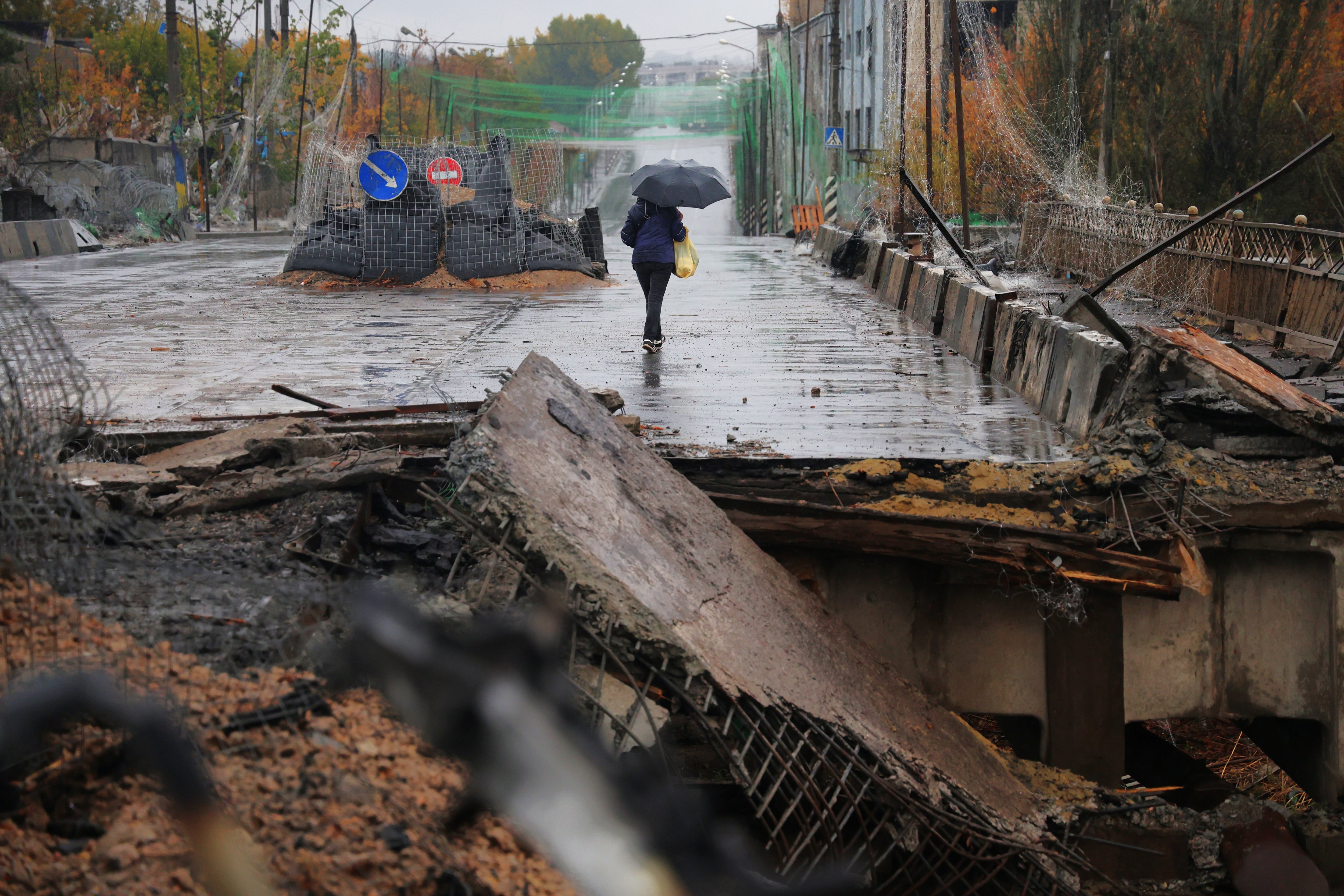 Una mujer avanza tras atravesar un puente bombardeado en Kramatorsk.