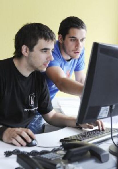 Dos jóvenes trabajan frente a un ordenador.