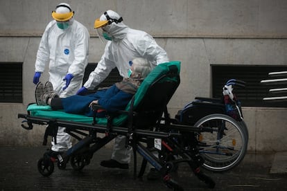 Personal sanitario traslada de su vivienda a una enferma contagiada por coronavirus, en Barcelona, el 30 de marzo.