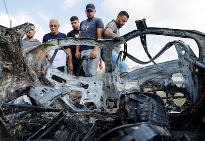 Un grupo de palestinos inspecciona el vehículo alcanzado por un misil israelí, en Zeita (Cisjordania), este sábado. 