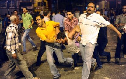 Egipcios auxilian a un joven herido durante enfrentamientos entre manifestantes y autoridades en la plaza Tahrir de El Cairo (Egipto).