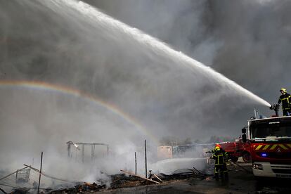 Bomberos lanzan agua a las llamas durante el incendio en el campamento de Calais.