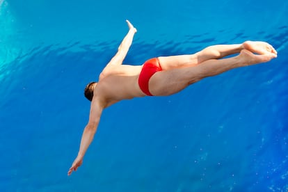 Un hombre se lanza hacia una piscina.