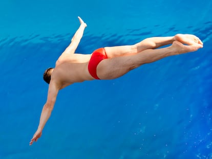 Un hombre se lanza hacia una piscina.