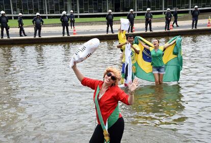 Manifestante, vestida como a presidenta Dilma Rousseff e segurando um boneco inflável do ex-presidente Lula, pede o impeachment da mandatária em protesto em Brasília, neste domingo.