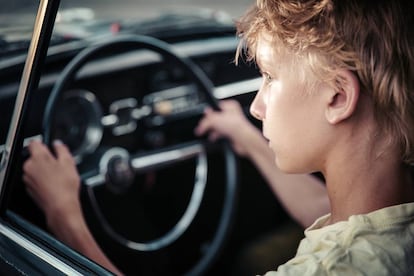 Un joven observa la carretera en el interior de un vehículo.